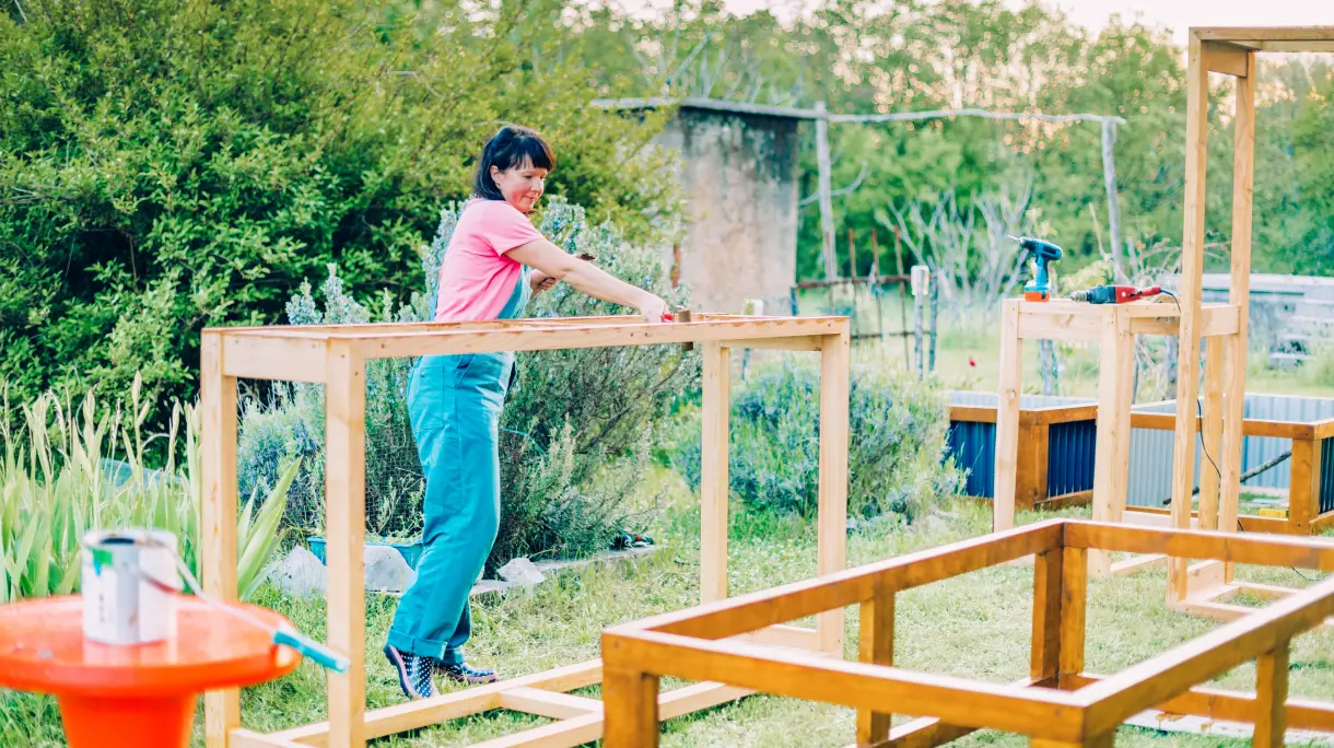 Woman assembling wooden planks for raised garden bed.