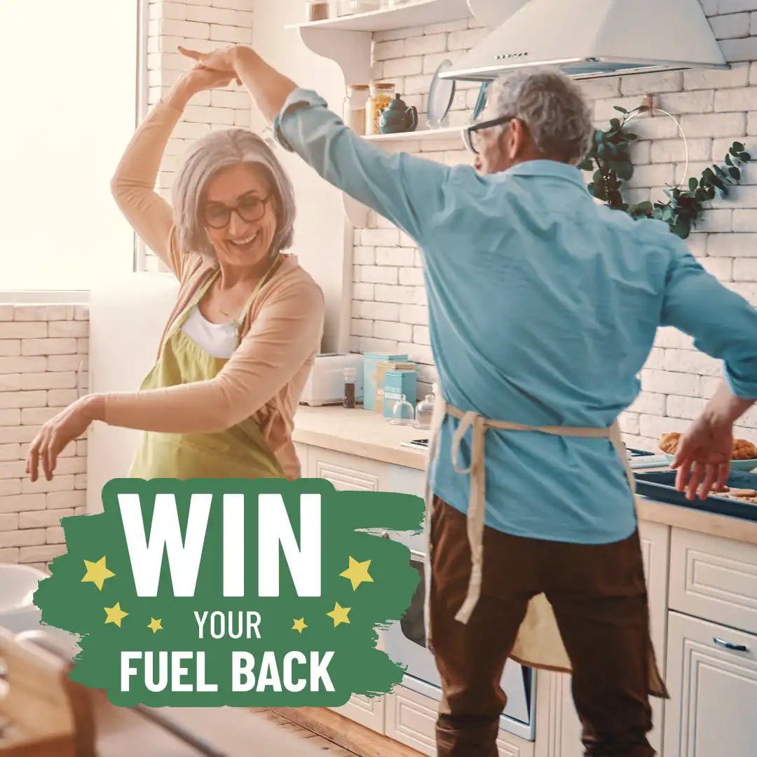 Elderly man and woman dancing in kitchen with Win Your Fuel Back logo overlay.