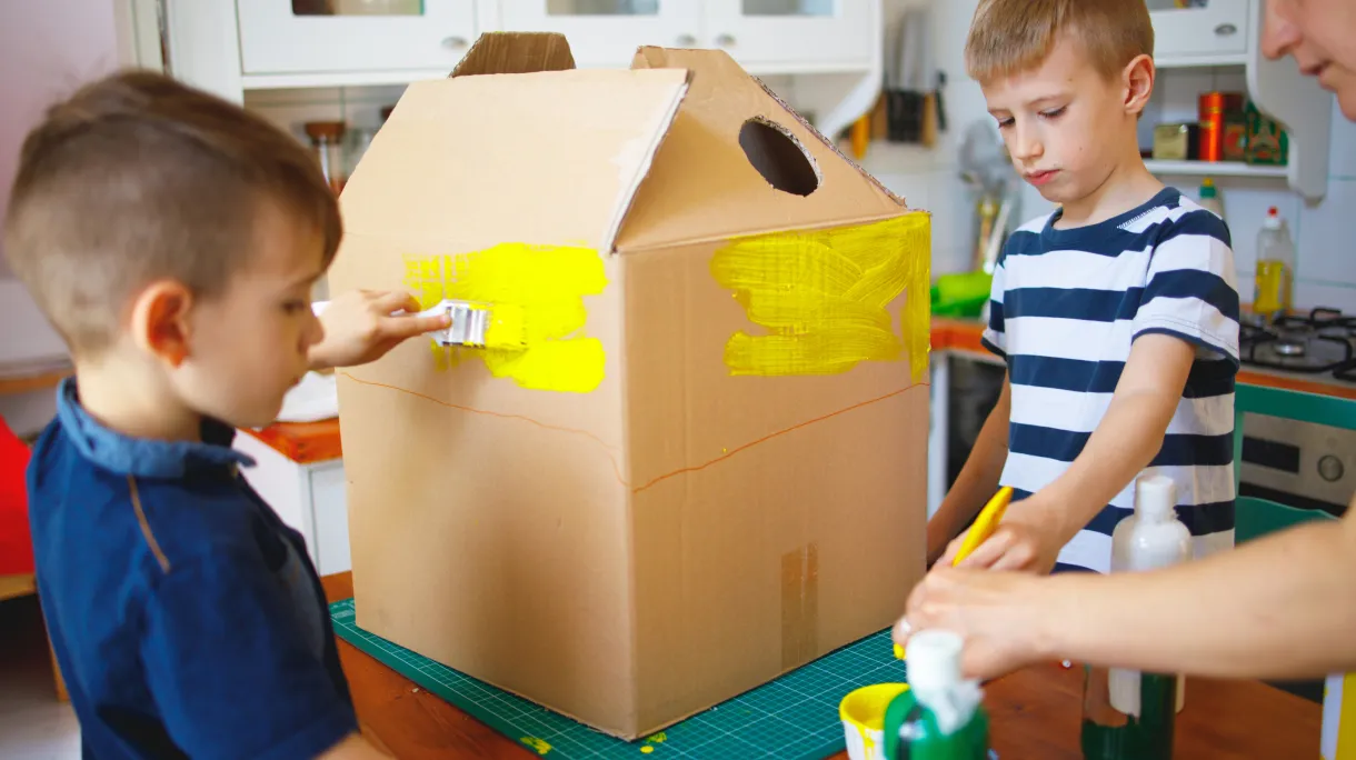 Children painting cardboard houses for summer craft project
