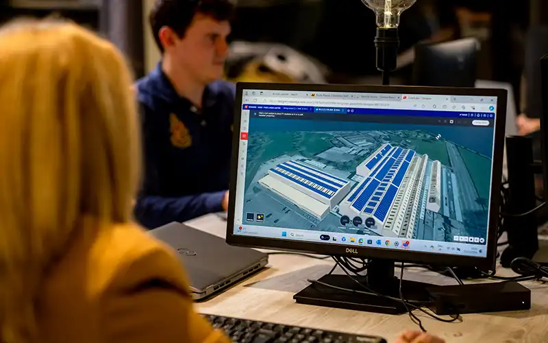 Lady sat in front of a computer screen working on solar panel planning for commercial building.